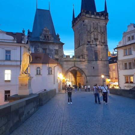 Die Karlsbrücke zeigt Menschen, die bei Dämmerung die historische Architektur bewundern.