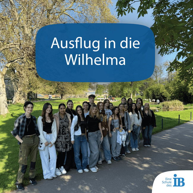 Eine Gruppe von Schülern posiert lächelnd im Wilhelma-Park während eines Ausflugs.