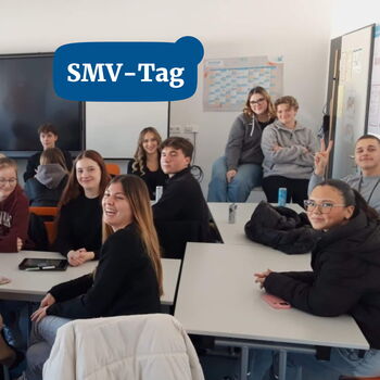 Eine Gruppe von Schülern sitzt und lächelt in einem Klassenzimmer während des SMV-Tags.
