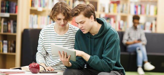Schülerin und Schüler schauen gemeinsam auf ein Tablet