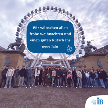 Eine große Gruppe von Menschen steht vor einem Riesenrad mit einer Weihnachtsbotschaft im Himmel.
