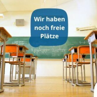 Ein leeres Klassenzimmer mit Tischen und Stühlen zeigt ein Schild mit der Aufschrift "Wir haben noch freie Plätze".