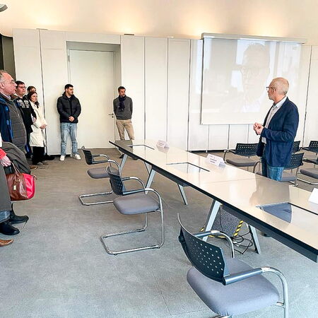Ein Mann hält eine Präsentation vor einer Gruppe von Menschen in einem modernen Konferenzraum.
