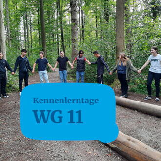 Eine Gruppe von Jugendlichen steht im Wald im Kreis und hält sich an den Händen während der Kennenlerntage.