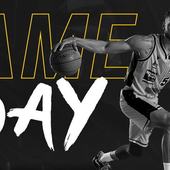 Ein Basketballspieler der MHP Riesen Ludwigsburg dribbelt dynamisch vor einem großen "Game Day"-Schriftzug.