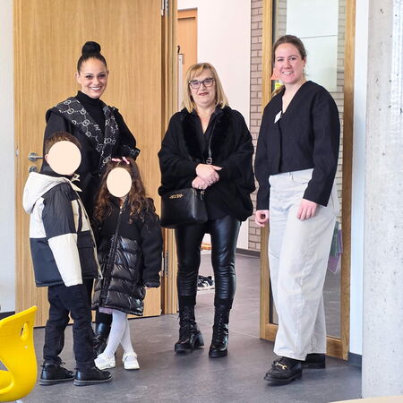 Besucher stehen lächelnd im Eingangsbereich der Grundschule während des Tags der offenen Tür.