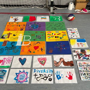Bunte Plakate mit Botschaften der Vielfalt sind auf dem Boden ausgebreitet, neben einem Basketball.