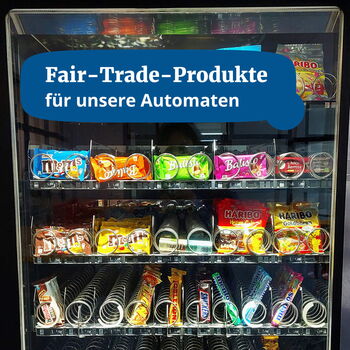 Ein Snackautomat bietet eine Auswahl an Fair-Trade-Produkten, darunter Balisto und Haribo, unter dem Slogan "Fair-Trade-Produkte".