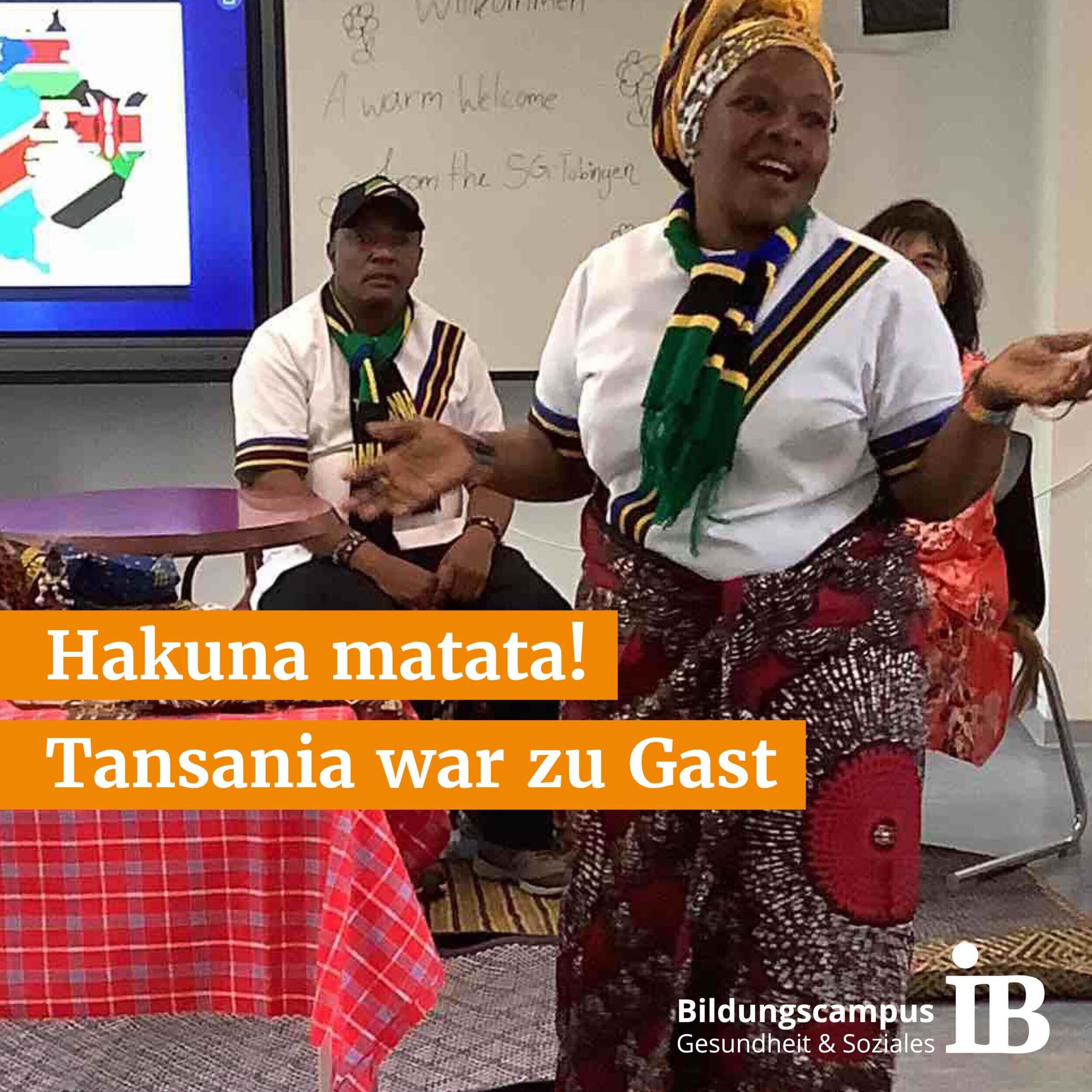 Eine Frau in traditioneller Kleidung tanzt fröhlich bei einem Tansania-Event vor einer kleinen Gruppe.