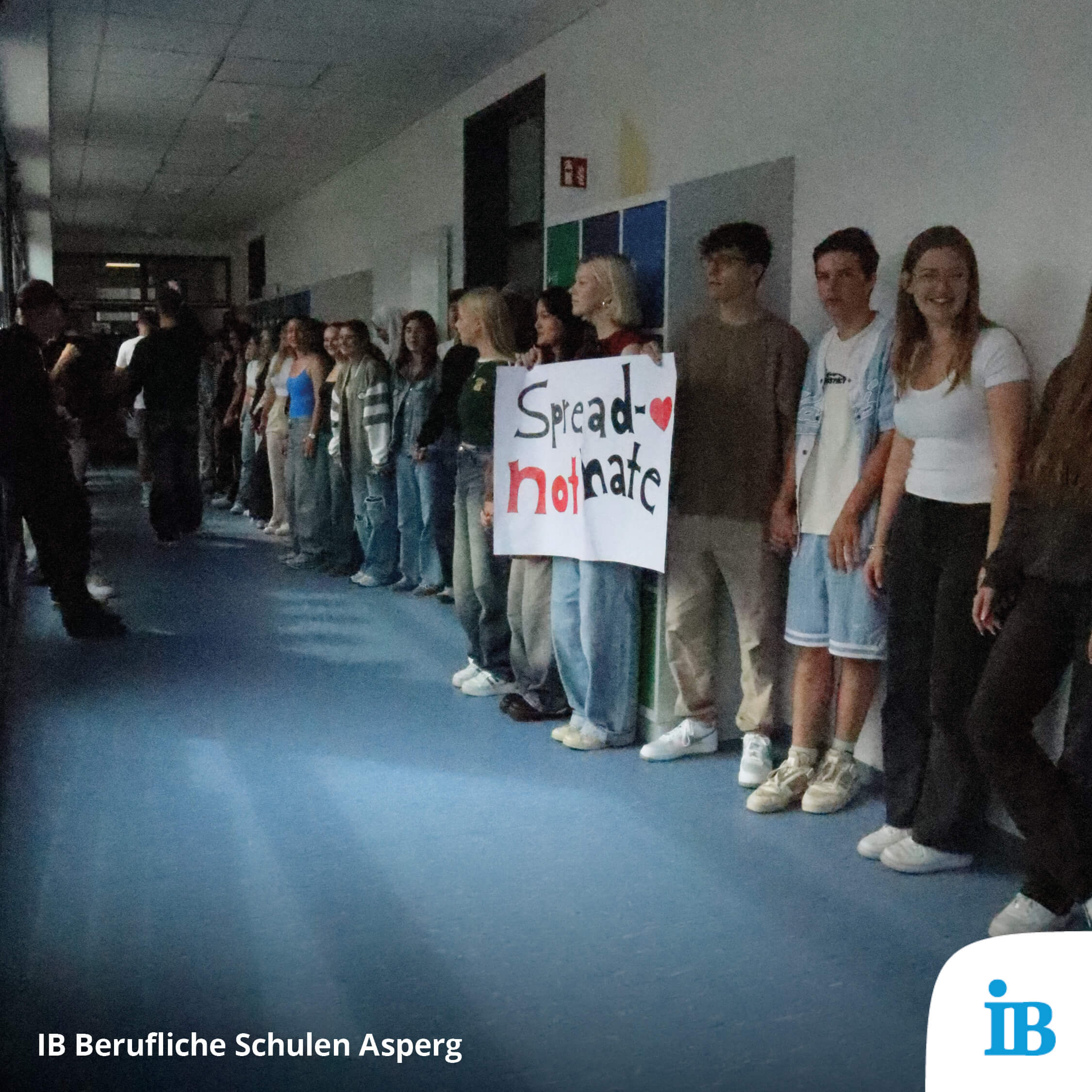 Schüler stehen in einem Flur und halten ein Plakat mit der Aufschrift "Spread love, not hate" in den IB Beruflichen Schulen Asperg.