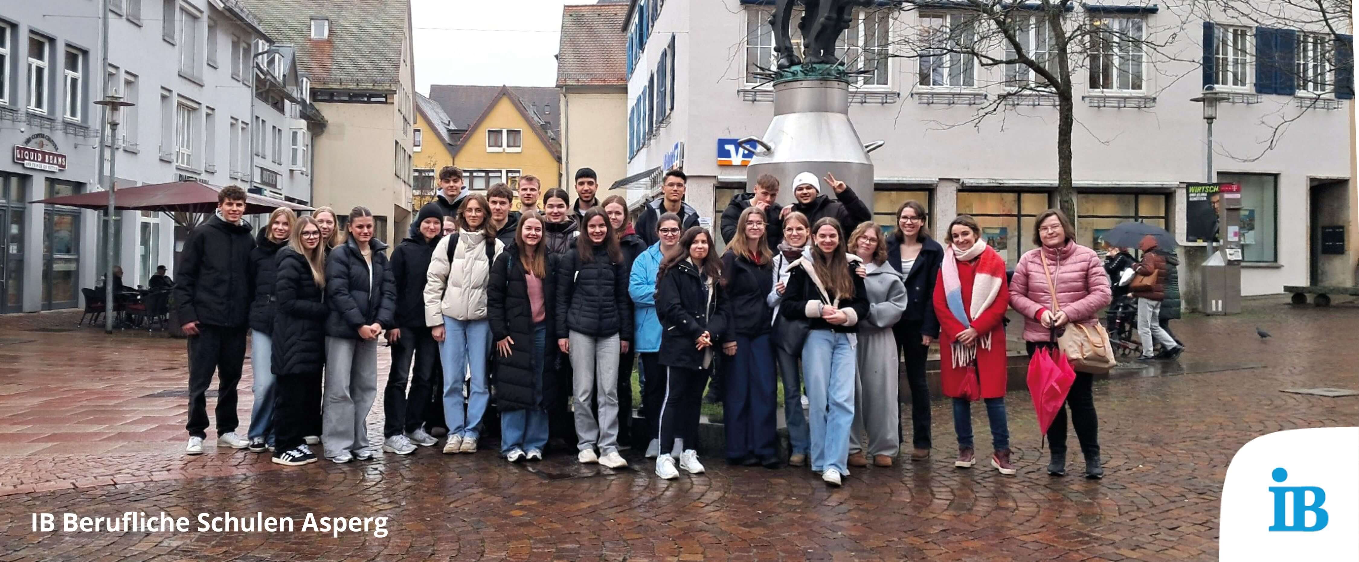 Eine Gruppe von Schülern und Lehrern posiert gemeinsam vor einem Denkmal in der Innenstadt während eines Theaterbesuchs.