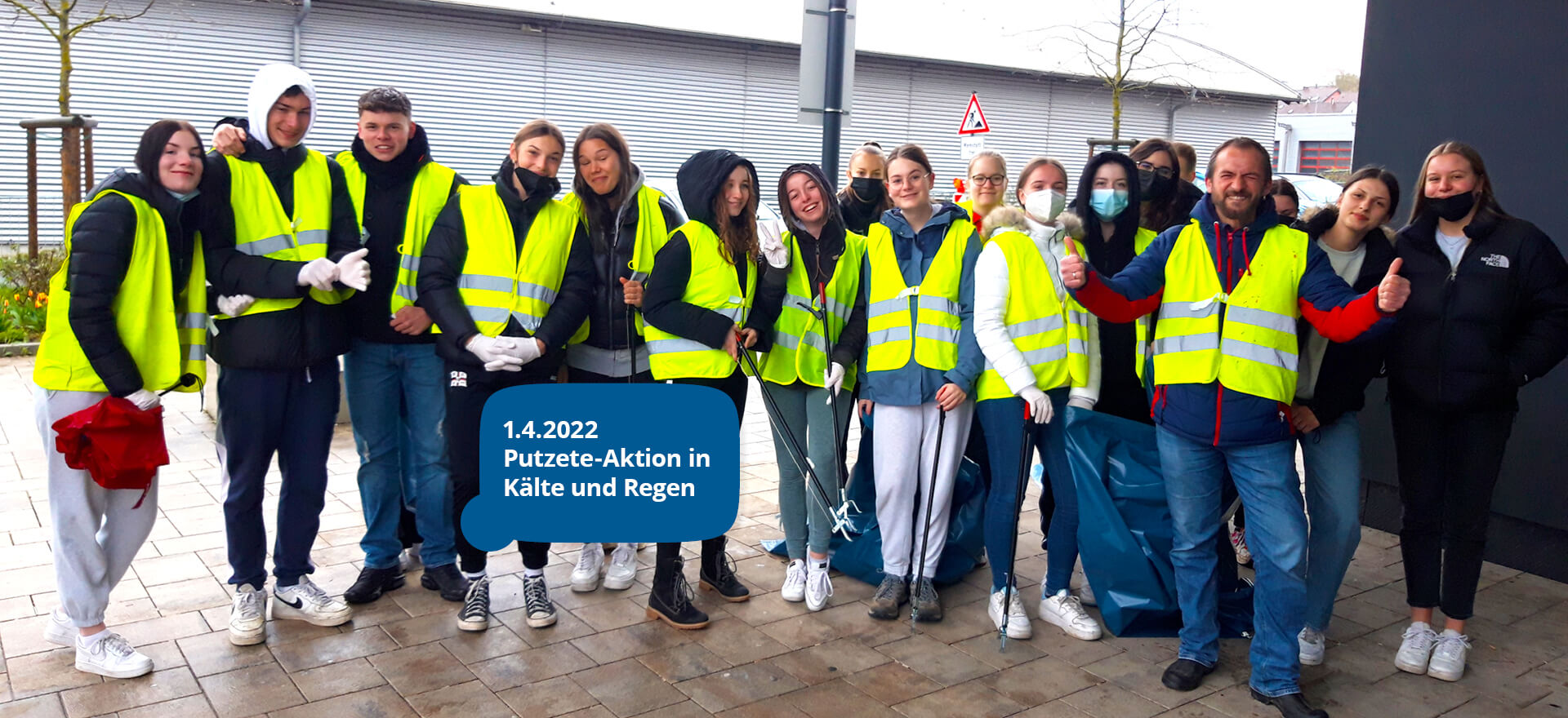 Eine Gruppe von Menschen in gelben Warnwesten nimmt am 1.4.2022 an einer Putzete-Aktion bei Kälte und Regen teil.