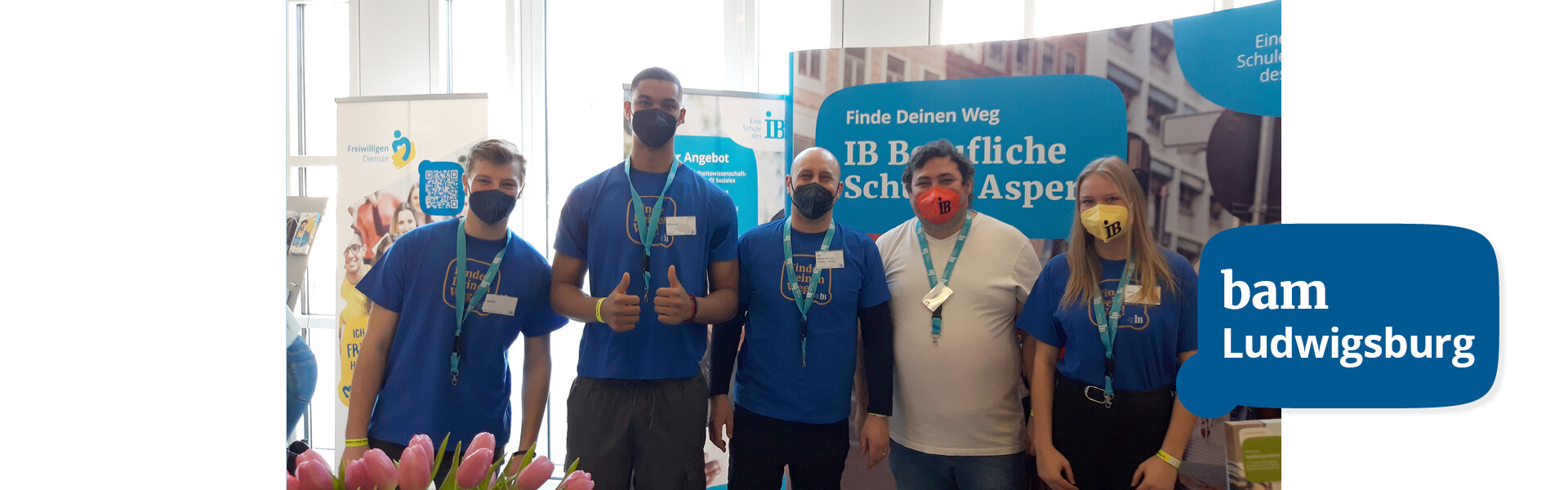 Eine Gruppe von fünf Personen mit Masken steht vor einem Stand auf einer Messe in Ludwigsburg.