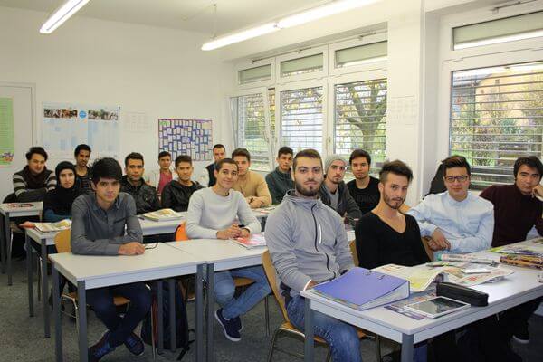 Eine Gruppe von Studierenden sitzt in einem hellen Klassenzimmer und blickt aufmerksam nach vorne.