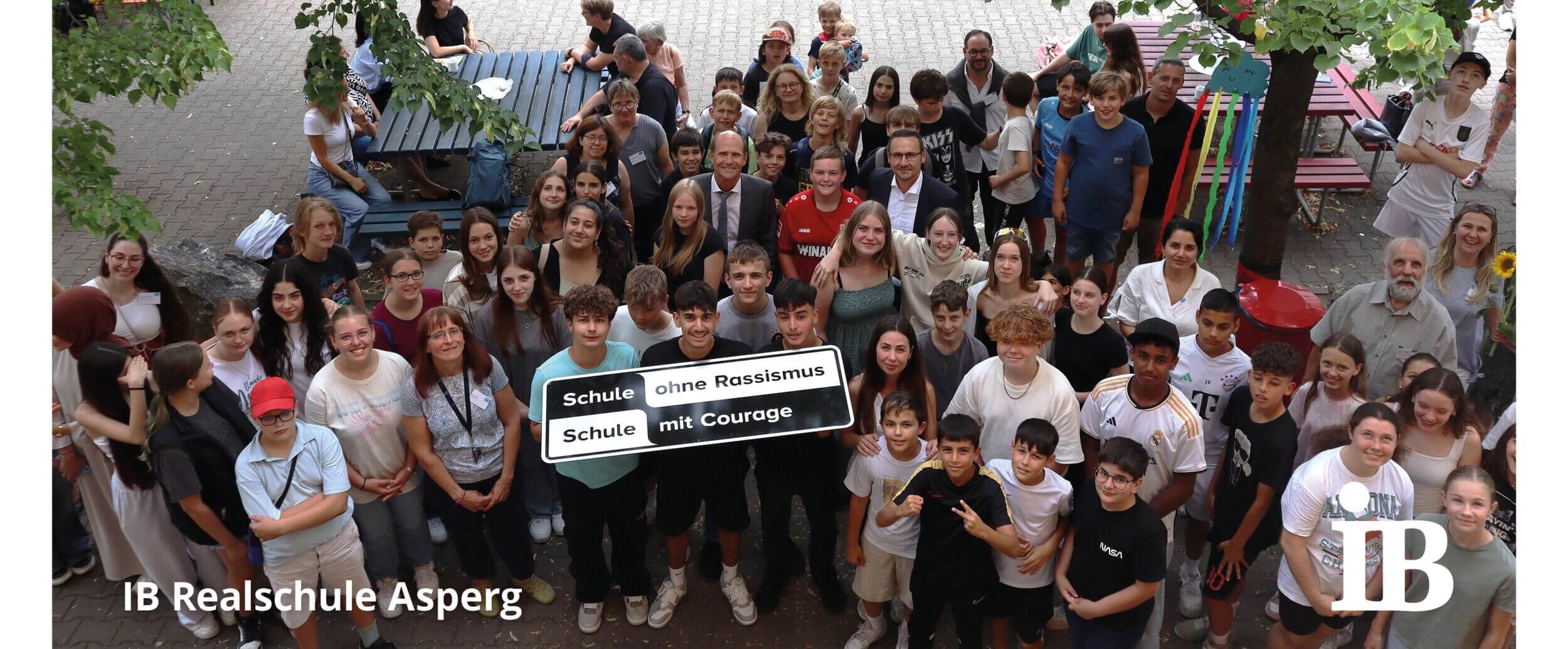 Eine große Gruppe von Schülern und Lehrern der IB Realschule Asperg posiert für ein Foto mit einem Schild gegen Rassismus.