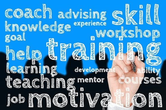 Eine Hand schreibt motivierende Begriffe wie "Training" und "Motivation" auf eine transparente Tafel vor blauem Hintergrund.