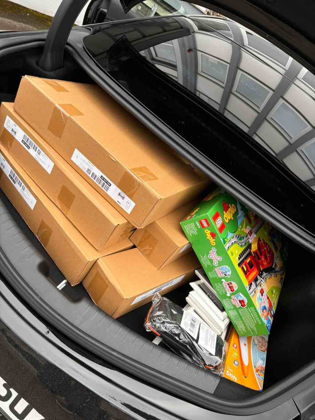 Ein Auto-Kofferraum ist mit Kartons und einem bunten Spielzeug-Set von LEGO Duplo gefüllt.