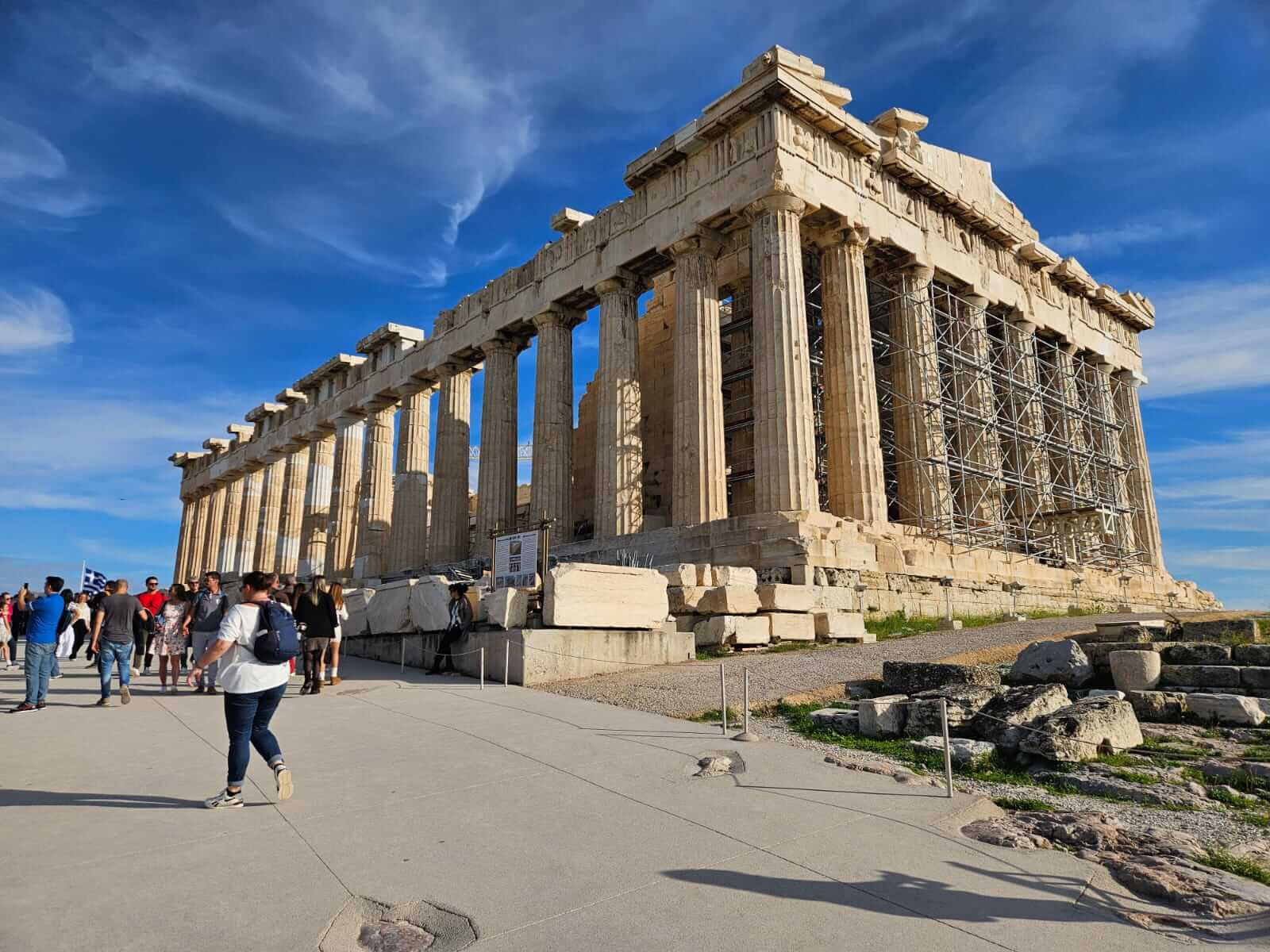Touristen erkunden das Parthenon in Athen bei klarem Himmel und Sonnenschein.