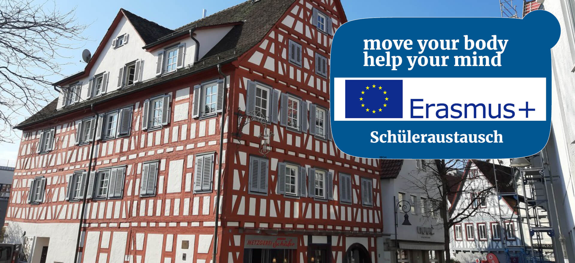 Ein traditionelles Fachwerkhaus steht neben einem Erasmus+ Banner für Schüleraustausch in Finnland.